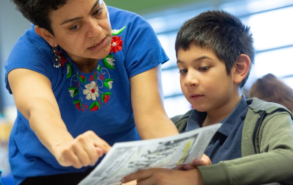 Teacher helping male student in classroom