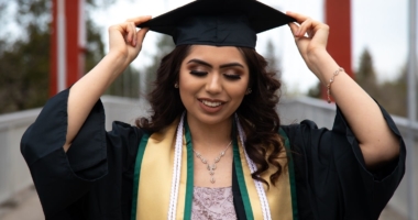 Hispanic female adjusting her graduation cap