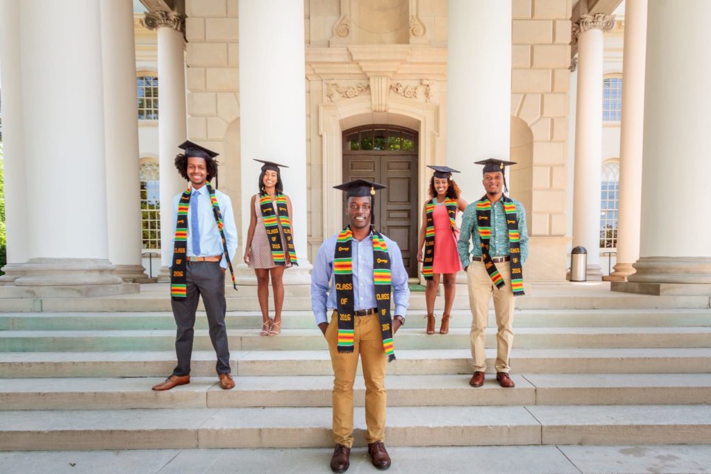 Male and female Black and Latino students posing with graduation caps and stoles
