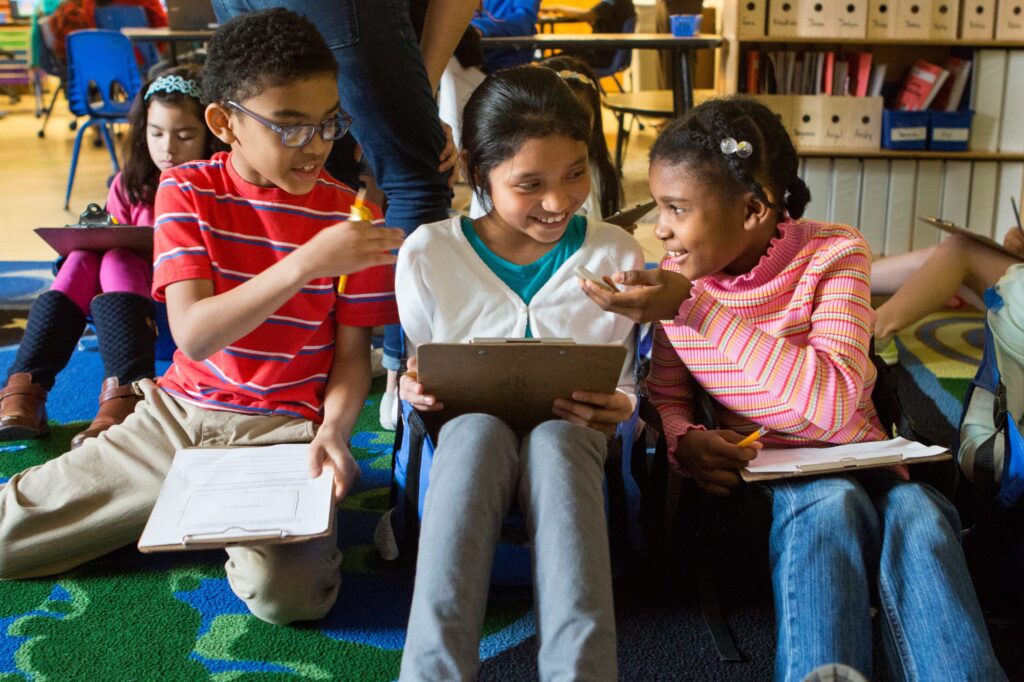 Group of three third graders huddled together.