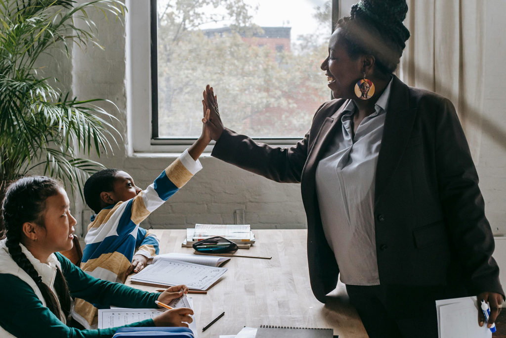 Teacher giving a high five to kids in a classroom