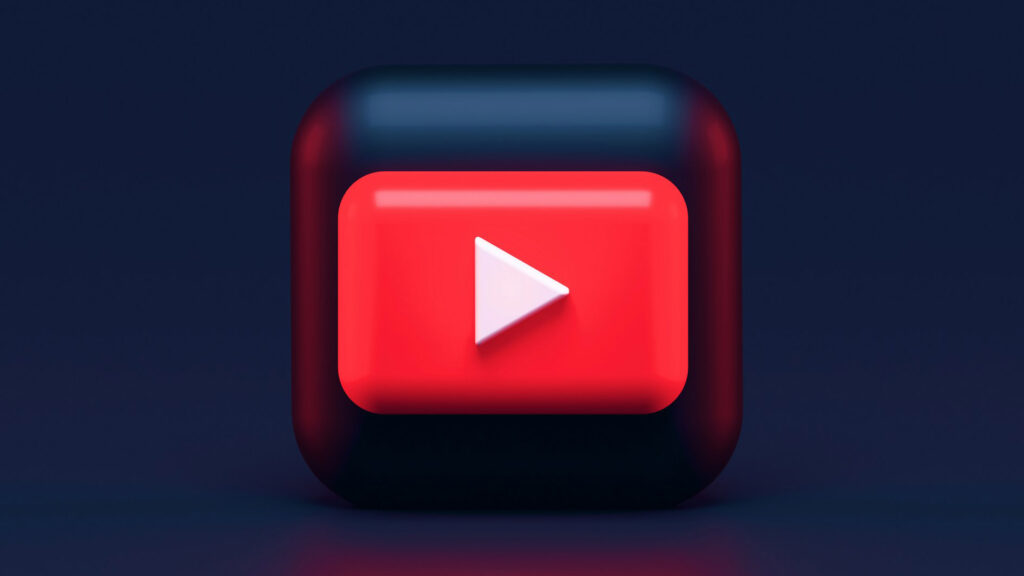 Icon of play video button of a white triangle in a red background on top of a dark surface