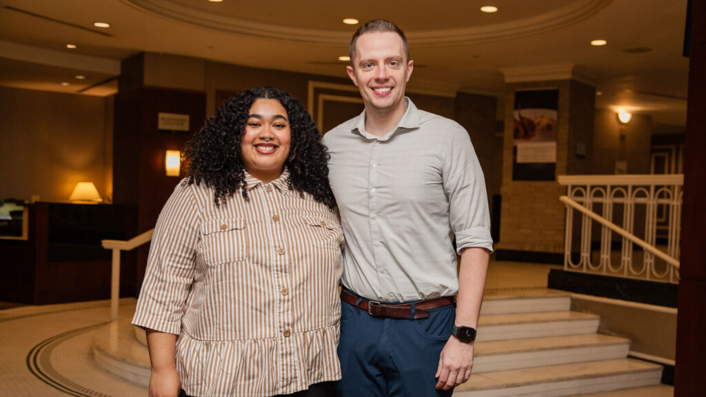 A man and woman standing together facing the camera and smiling
