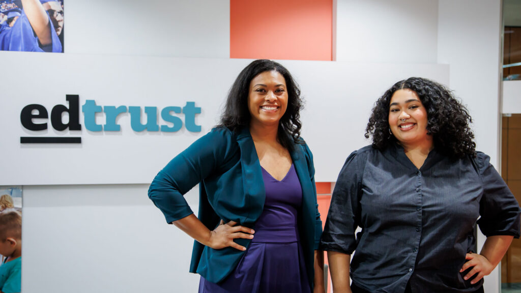 Dr. Rogers and Tatiana smiling for the camera with the EdTrust sign in the background