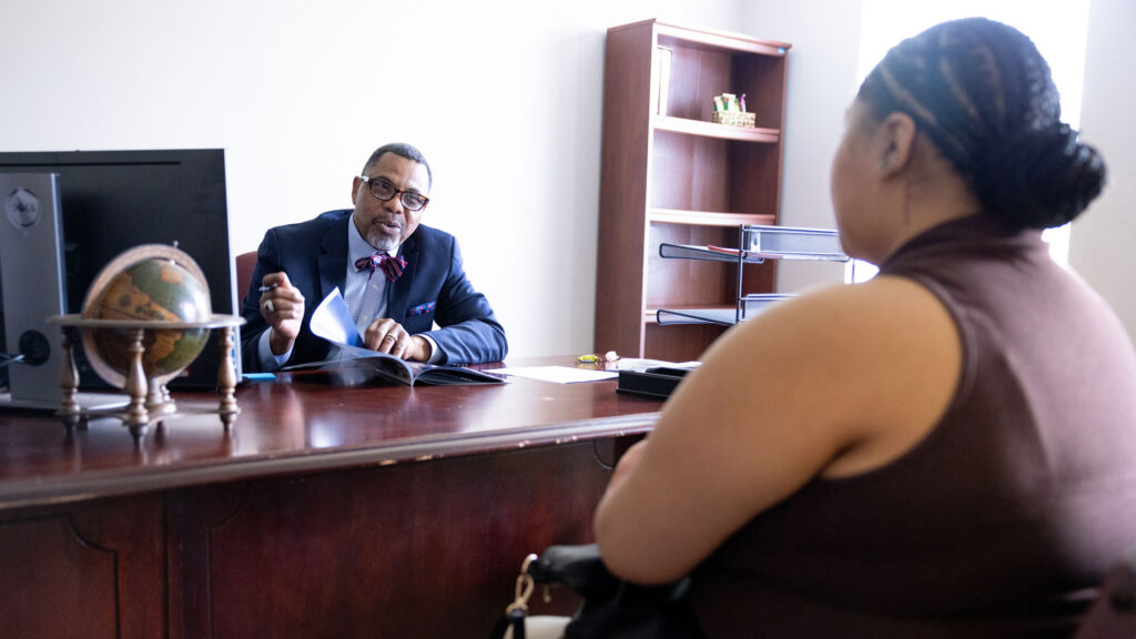 Black male advisor speaking to a black female student in an office on a college campus